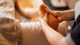 Woman receiving massage on her legs Woman receiving professional relaxation massage on her foot at Spa salon. Client lying covered with towel on medical couch, close-up on leg